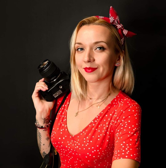 kobieta w czerwonej bluzce i opasce trzymająca aparat fotorgraficzny