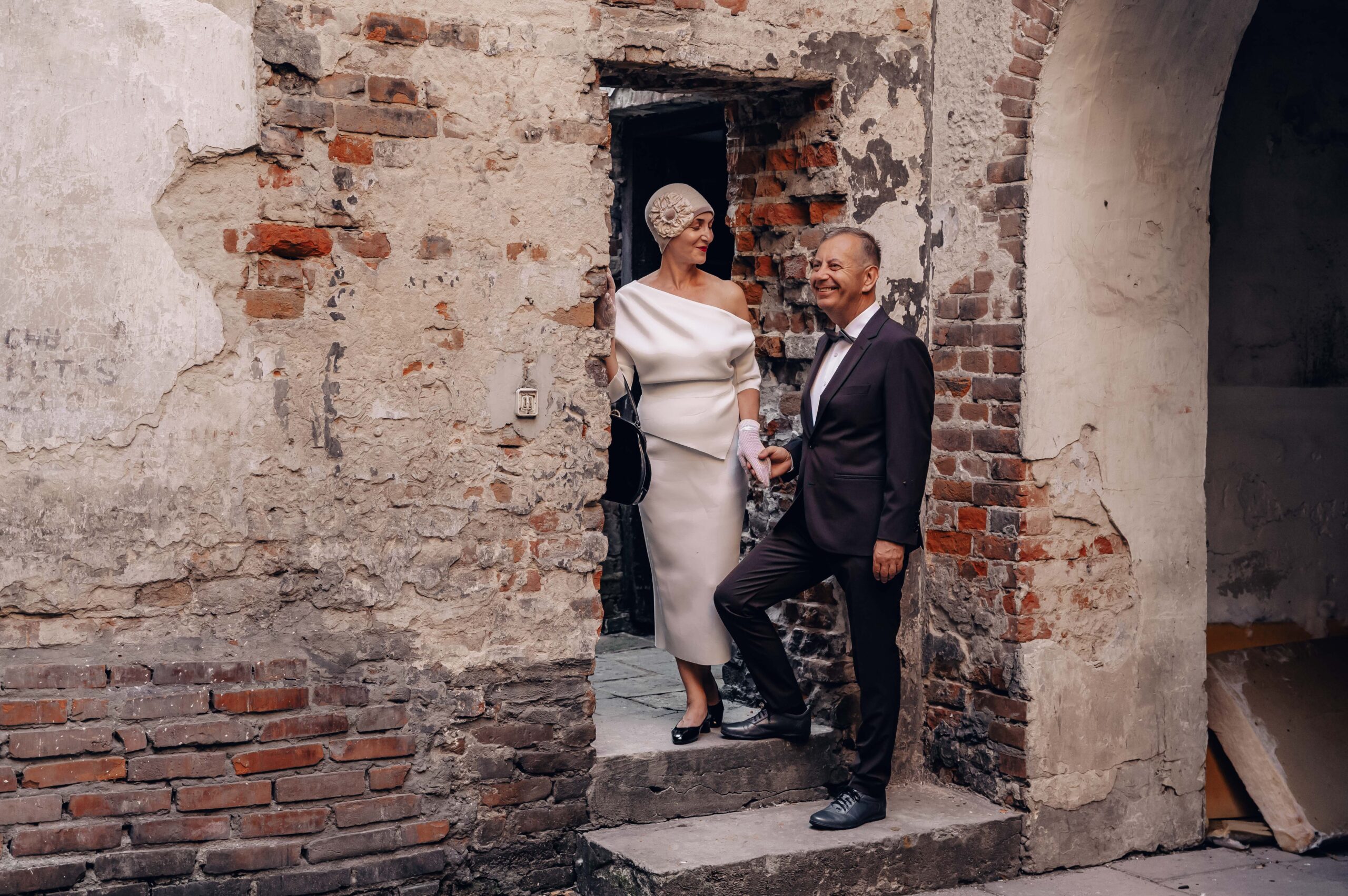 kobieta i mężczyzna strojach w stylu retro stojąca między starymi murami