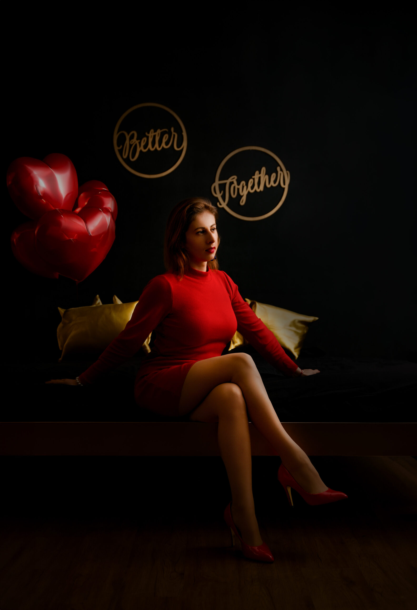 kobieta w czerwonej sukience siedząca na łóżku w klimatycznym ciemnych pokoju