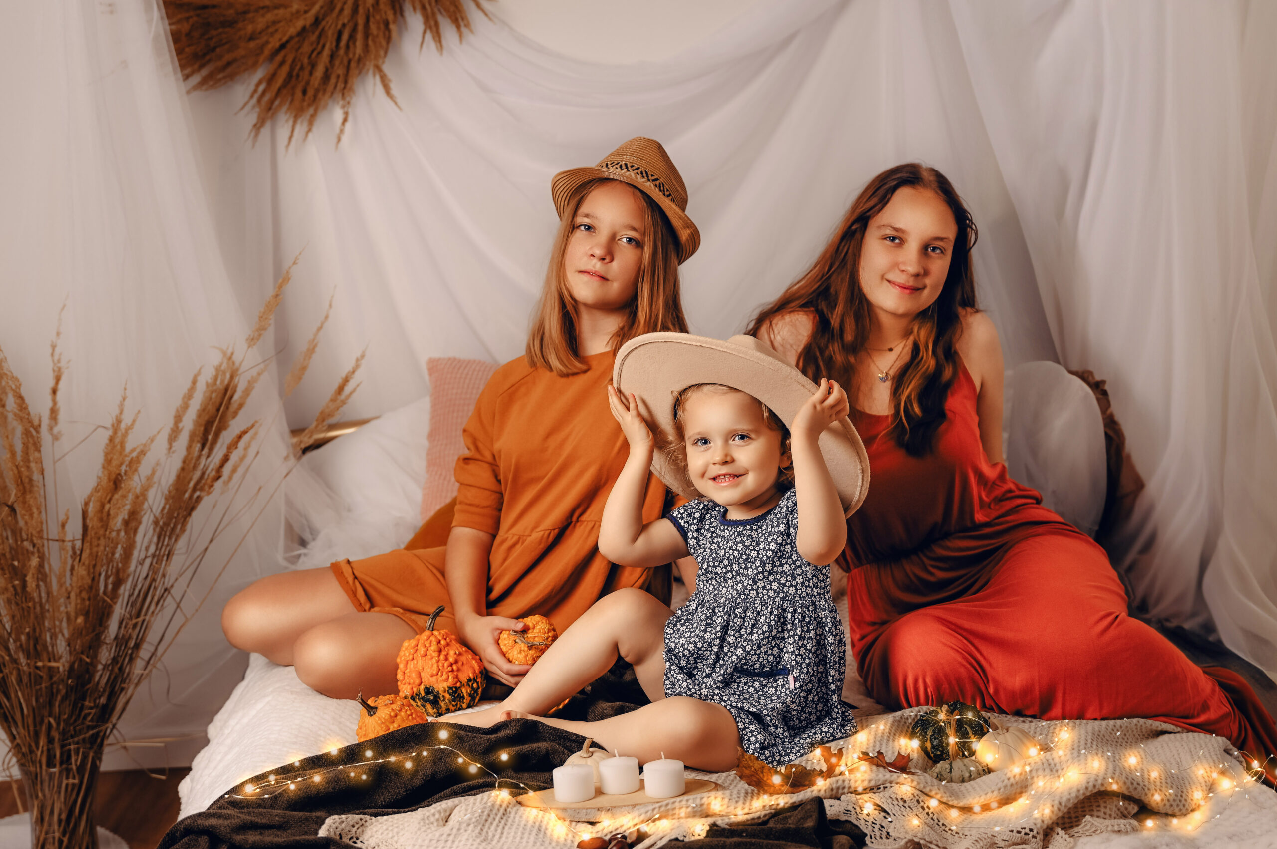 trzy dziewczynki w różnym wieku w sesji jesiennej na łóżku