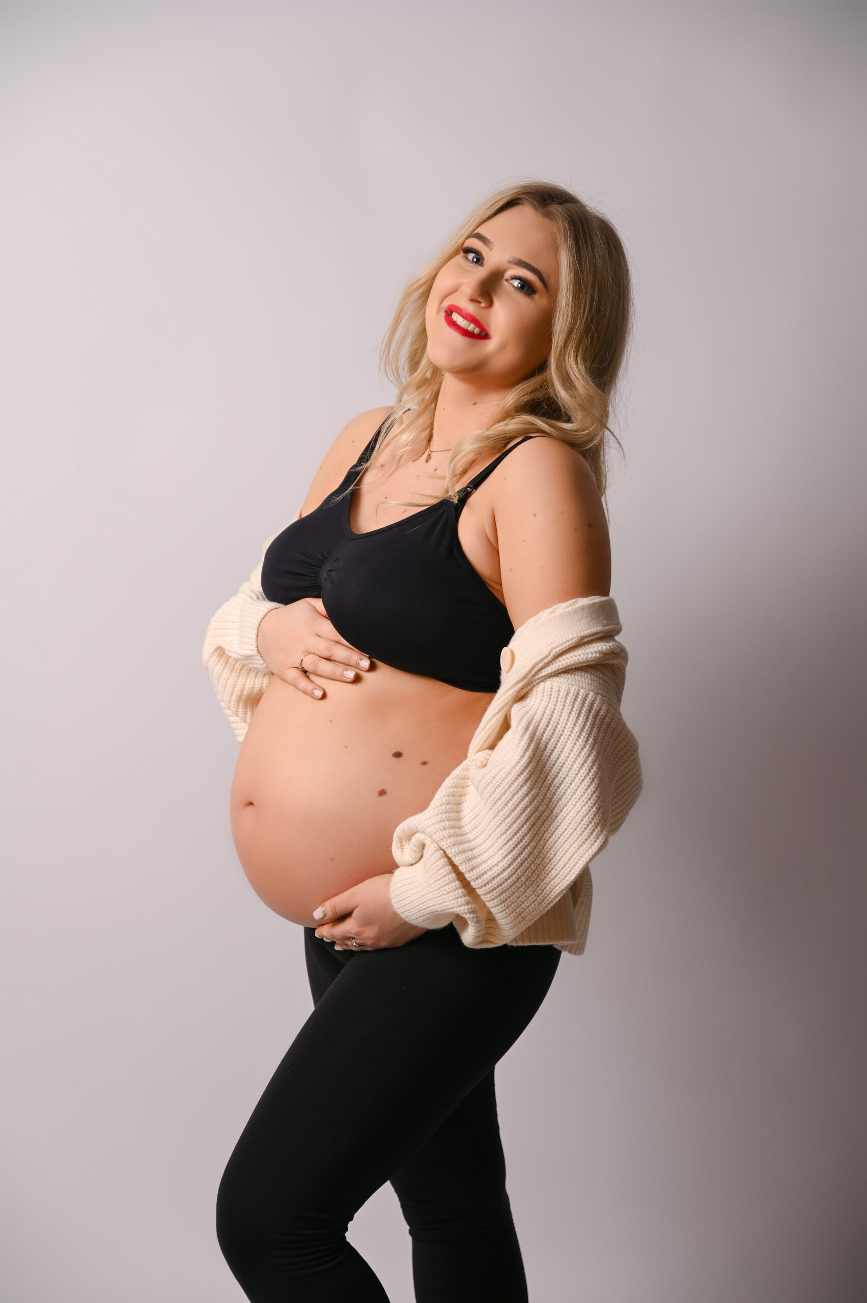 kobieta w ciąży z pięknym uśmiechem w białym sweterku