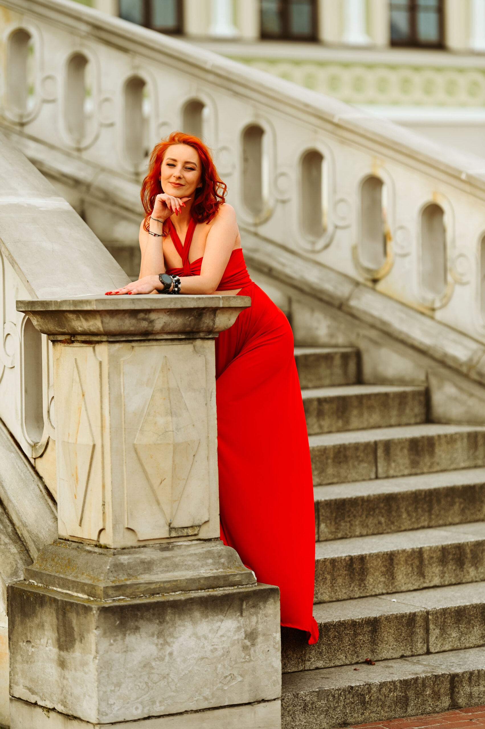 kobieta w długiej czerwonej sukience na starych schodach