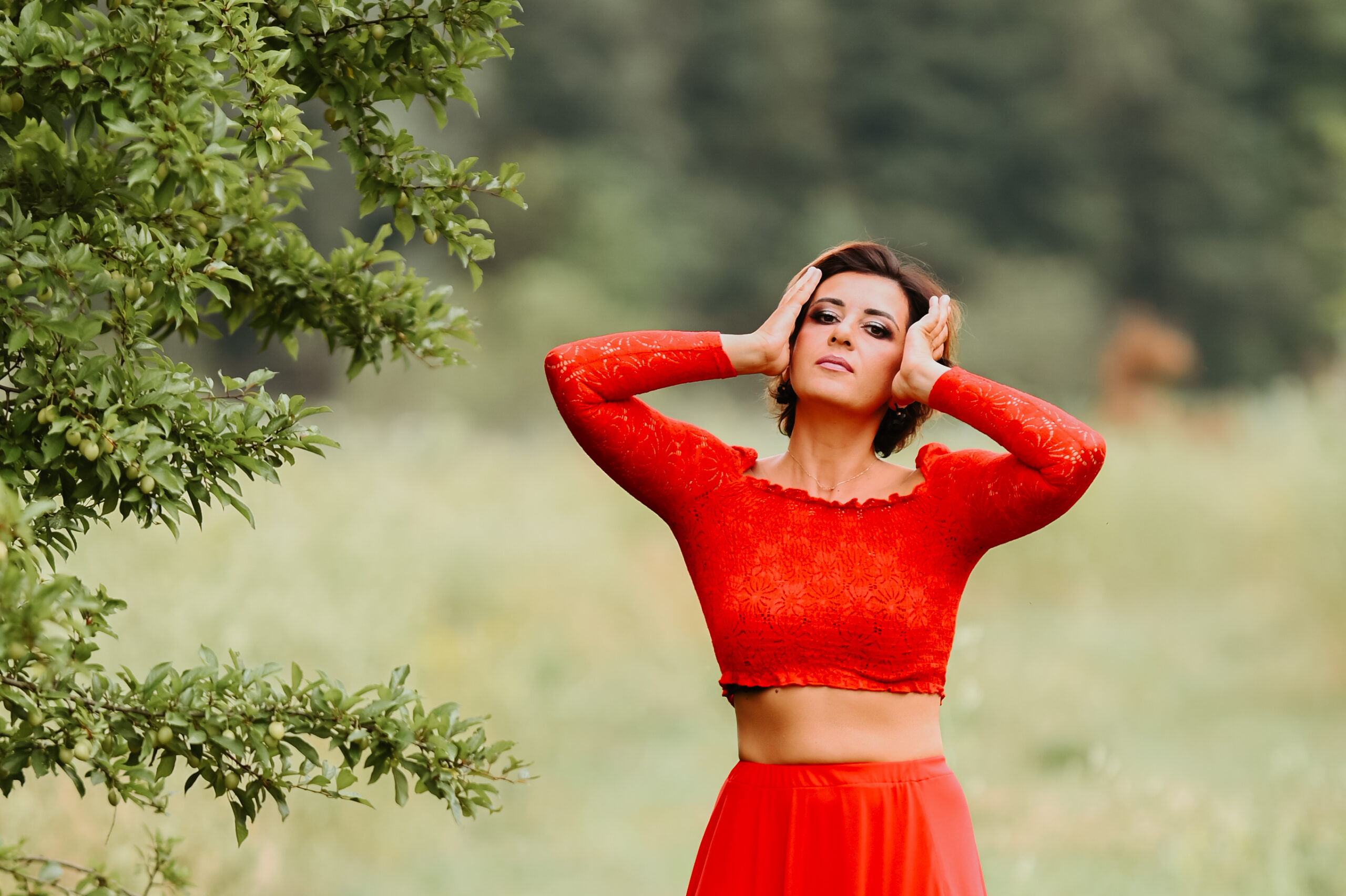 kobieta w makijażu i czerwonej sukience trzymająca się za głowę