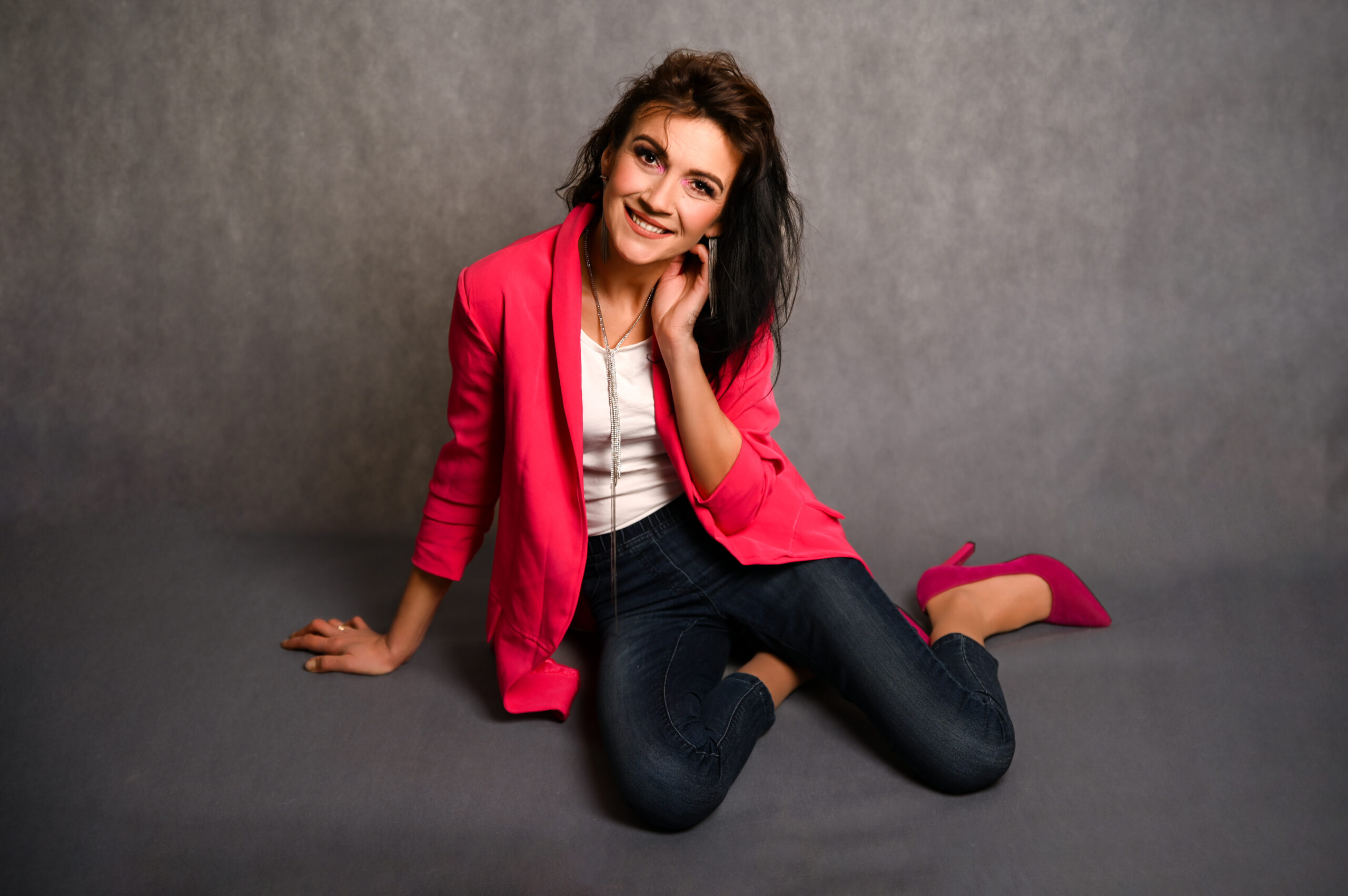 kobieta w różowej marynarce siedząca na podłodze