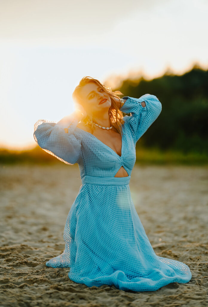 kobieta w niebieskiej sukience na plaży przy zachodzie słońca